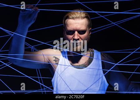 Porträt von bärtigen Mann verwickelt in weißen Fäden in ultravioletten Stockfoto