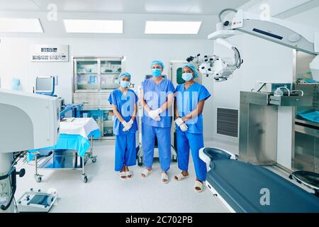Serious zuversichtlich Chirurgen in Scrubs und medizinische Masken stehen im Operationssaal Stockfoto