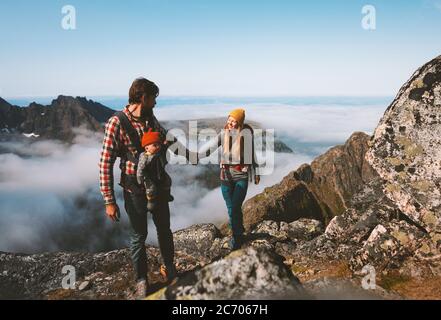 Familie Wandern Mann und Frau Reisen mit Baby-Träger im Freien gesund Lifestyle Urlaub in den Bergen Mutter und Vater hält Hände Öko-Tourismus s Stockfoto