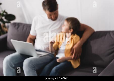 Selektive Fokussierung von Vater und Sohn auf dem Sofa sitzen, reden und mit Laptop Stockfoto