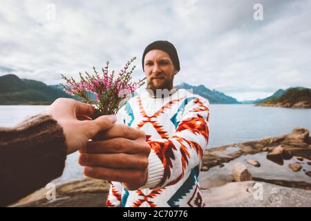 Bärtiger Mann Blumen Blumenstrauß romantische Paar in der Liebe im Freien Beziehung Lifestyle Freunde zu Fuß zusammen am Strand in Norwegen Stockfoto