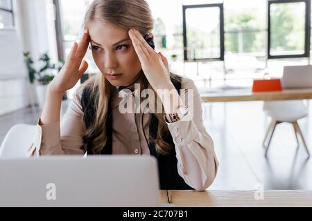 Selektiver Fokus des müden Bedieners auf Kopfschmerz des Headsets Stockfoto