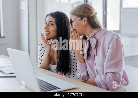Selektive Konzentration attraktiver Geschäftsfrauen, die in der Nähe von Laptops im modernen Büro klatschen Stockfoto
