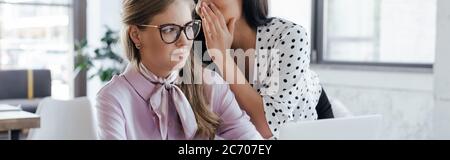 Website-Header von Geschäftsfrau flüsternd in das Ohr des Kollegen in Brille, während Klatsch im Büro Stockfoto