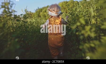 Kind läuft durch das Gras Baby Mädchen spielen im Freien Familienurlaub Reise Sommersaison Natur Stockfoto