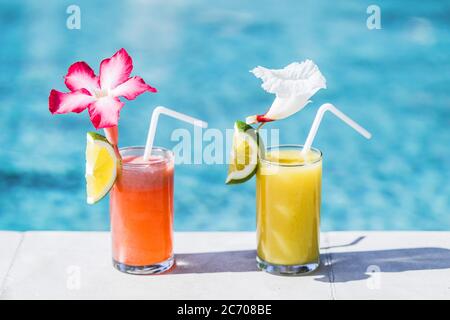 Zwei Gläser mit frischem kalten Fruchtsaft am Pool. Mit Stroh, Slice von Kalk und tropische Blume Stockfoto