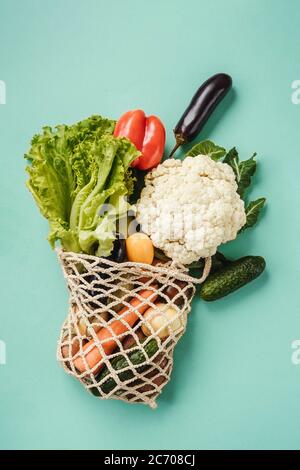 Verschiedene frische Gemüse in Öko-Tasche auf türkisfarbenem Hintergrund. Vegetarisches Gericht vom Markt in Saitenbeutel. Zero Waste Konzept. Stockfoto