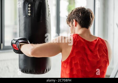 Athletischer Mann in Sportbekleidung und Boxhandschuhen Training mit Boxsack Stockfoto