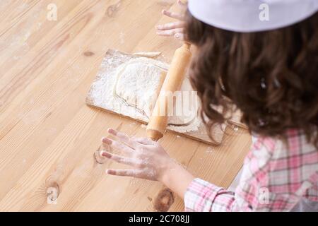 Vorbereitung des Tests. Holztisch. Weißes Mehl. Kleine Hände Stockfoto