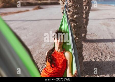 Frau liegt in Hängematte zwischen Palmen am Strand Stockfoto