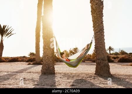 Frau liegt in Hängematte zwischen Palmen am Strand Stockfoto