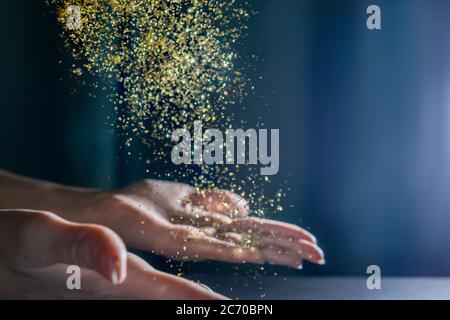 Hände mit fliegenden Pailletten und funkelt. Licht auf Hintergrund. Festliches Konzept. Stockfoto