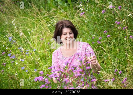 Frau mittleren Alters auf einer schönen wilden Wiese im Sommer Stockfoto