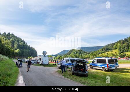 Oppenau, Deutschland. Juli 2020. Medienvertreter und Polizeikräfte stehen in der Nähe eines Hauses für Sportler, das als Treffpunkt der Polizei dient. Ein großes Polizeikontingent hat nach einem bewaffneten Mann gesucht, der die Inspektionsbeamten während einer Inspektion entwaffnet und geflohen haben soll. Die Polizei sucht nun den Mann im Wald neben dem Gelände. Quelle: Philipp von Ditfurth/dpa/Alamy Live News Stockfoto