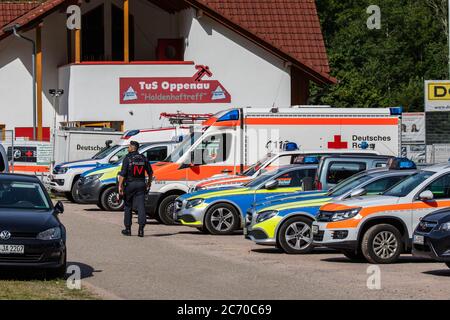 Oppenau, Deutschland. Juli 2020. Ein Polizist geht über den Parkplatz des Hauses eines Sportlers, der als Treffpunkt für Polizei und Rettungsdienste dient. Ein großes Polizeikontingent sucht seit dem Morgen nach einem bewaffneten Mann, der die Kontrollbeamten bei einem Scheck entwaffnet und geflohen sein soll. Die Polizei sucht nun den Mann in den Wäldern um das Dorf herum. Quelle: Philipp von Ditfurth/dpa/Alamy Live News Stockfoto