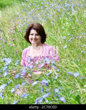 Frau mittleren Alters auf einer schönen wilden Wiese im Sommer Stockfoto