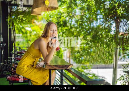 Junge Frau trinkt sommerliche Fruchtgetränke auf einer Sommerterrasse Stockfoto