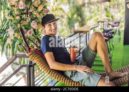 Der junge Mann trinkt sommerliche Fruchtgetränke auf der Sommerterrasse Stockfoto