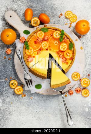 Käsekuchen mit Orangenscheiben und Kumquat auf grauem Steingrund. Draufsicht. Stockfoto