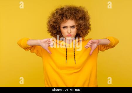 Nicht Gefallen! Porträt von unzufrieden frustriert lockig-haarige Frau im städtischen Stil Hoodie zeigt Daumen nach unten, Kritik unzufrieden mit schrecklichen Service. Stockfoto