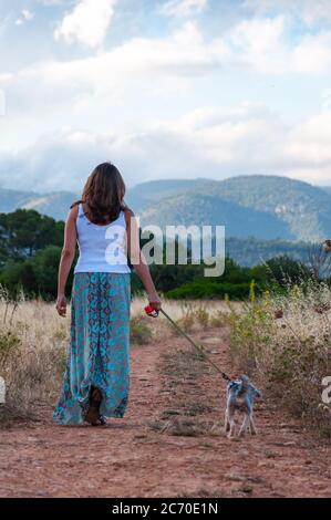 Frau, die allein mit ihrem Hund im Wald geht Stockfoto