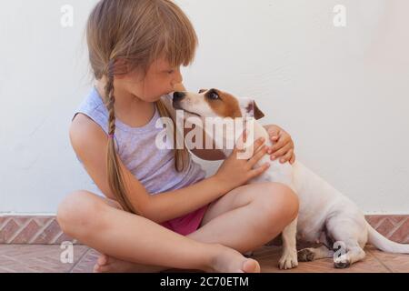 Schöne kleine Mädchen Kind und Hund spielen zusammen Stockfoto