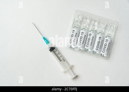 Spritze und Ampullen mit Impfstoff gegen Coronaviren Influenza auf weißem Hintergrund. Fläschchen mit Etikett Covid-19. Stockfoto
