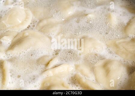 Kochen von Knödeln in einer Pfanne mit Wasser, Fleisch in Teigbrötchen. Draufsicht. Stockfoto