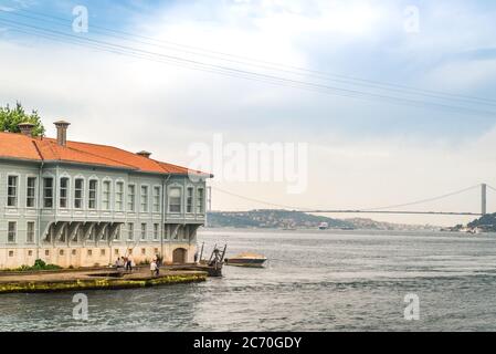 Eine Szene in Istanbul, Türkei, die eine Gruppe von Männern zeigt, die vom Ufer aus fischen, und eine moderne Brücke, die die Bosporus-Straße überquert Stockfoto