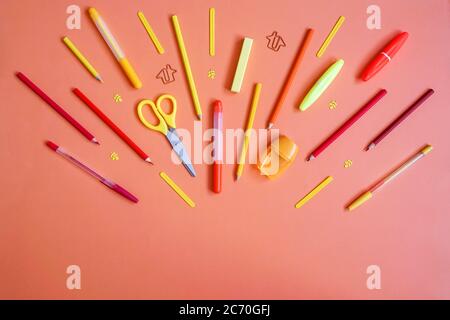 Schreibwaren auf orangefarbenem Hintergrund. Flach liegend. Als Feuerwerk von Werkzeugen, Farbverlauf Farben. Stockfoto