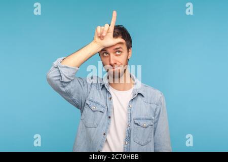 Ich habe Arbeit verloren! Porträt von depressiven Mann in Arbeiter Denim-Shirt zeigt Verlierer Geste, L Finger Zeichen auf Stirn, verärgert über Entlassung, unglücklicher Tag. indo Stockfoto