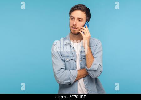 Porträt von jungen gut aussehenden Geschäftsmann in lässigen Denim-Shirt reden am Telefon, mit ernsthaften mobilen Gespräch mit Partner, wichtige Anruf. Stockfoto