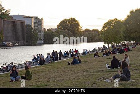 Berlin, Deutschland. Juli 2020. Auf den Wiesen der East-Side-Gallery sitzen Menschen und genießen den Sonnenuntergang an der Spree. Quelle: Paul Zinken/dpa/Alamy Live News Stockfoto