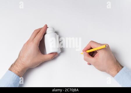 Männliche Hände hält Pille Flasche und Stift. Arzt schreibt Rezept Konzept. Draufsicht. Stockfoto