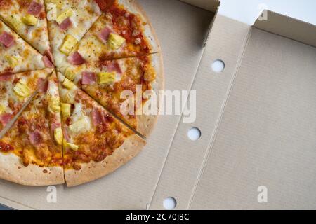 Nahaufnahme hawaiianische Pizza in brauner Papierkassette. Draufsicht Stockfoto