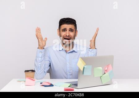 Überstunden, Überarbeitungskonzept. Schockiert erschreckt Mann Mitarbeiter sitzt im Büro Arbeitsplatz, Heben die Hände schreien vor Angst, klebrige Notizen rund um Remindin Stockfoto