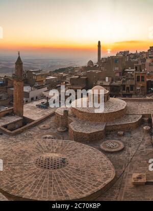 Mardin, Türkei - Januar 2020: Altstadt von Mardin Stadtbild mit Dach eines türkischen Hammam und Minarette bei Sonnenuntergang Stockfoto