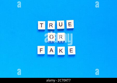 ECHTE ODER GEFÄLSCHTE Wort Buchstaben auf blauem Hintergrund. Flaches Layout. Draufsicht. Stockfoto