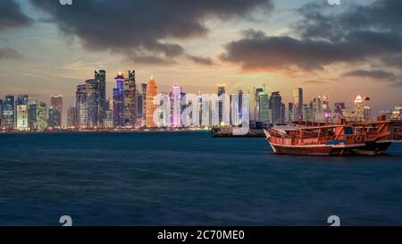 Doha, Katar - Februar 2019: Doha Katar Skyline mit traditionellen katarischen Dhow Boote im Hafen mit dramatischen Himmel und Wolken Stockfoto