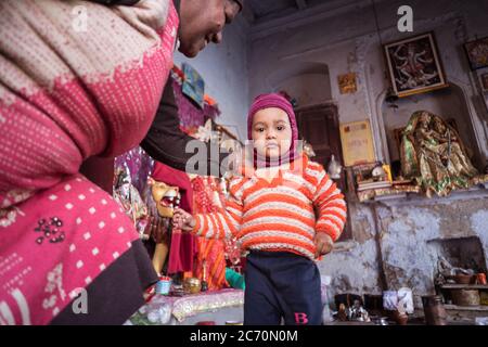 Neu Delhi / Indien - 18. Februar 2020: Niedlicher kleiner Junge mit rotem Hut im buddhistischen Zimmeraltar Stockfoto