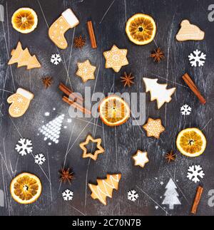 Weihnachts-Ingwerkekse, getrocknete Orange, Zimt, Sternanis und Schneeflocken auf schwarzem Stein Hintergrund. Draufsicht. Stockfoto