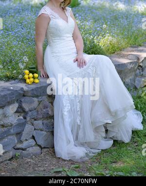 Stadtfotos einer Braut, die ein weißes Kleid trägt und einen gelben Tulpenstrauß in den Händen hält Stockfoto
