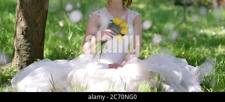 Stadtfotos einer Braut, die ein weißes Kleid trägt und einen gelben Tulpenstrauß in den Händen hält Stockfoto