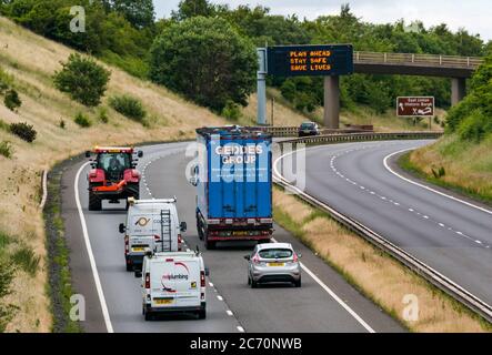 East Lothian, Schottland, Großbritannien, 13. Juli 2020. A1 Covid-19 Reiseberatung Schottland geht in Phase 3 auf einer Überfahrbrücke mit der neuen Iteration der Botschaft: 'Plan ahead, Stay Safe, Save Lives'. Dies ist die vierte Iteration der Coronavirus-Slogans, die von der schottischen Regierung während der Pandemie verwendet wurden. Die zweispurige Straße ist viel geschäftiger und fast wieder auf normale Verkehrsniveaus Stockfoto