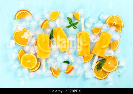 Obst hausgemachter Popsicle mit Scheiben von Orange und Eiswürfeln auf hellblauem Hintergrund. Draufsicht. Stockfoto