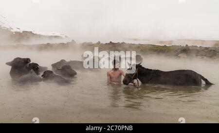 Guroymak, Bitlis, Türkei - Februar 2020: Kleiner Junge und sein Pferd im Thermalwasser, Freundschaft mit Haustieren, Tierdusche Stockfoto