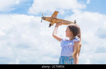 Reisen Sie mit dem Flugzeug. Halten Sie träumen. Kind spielen Holzspielzeug Flugzeug. Studieren Sie Geographie. Träume vom Reisen. Geschichte über Sommerurlaub. Kleines Mädchen halten Holzflugzeug. Phantasie. Stockfoto