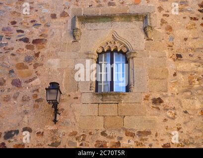 Fassade und verschlungenes Fenster im historischen Zentrum von Caceres, Extremadura, Spanien. UNESCO-Weltkulturerbe. Sonnenschein am späten Nachmittag. Stockfoto