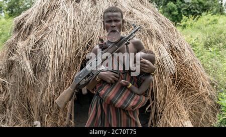 Mago Nationalpark, Omo River Valley, Äthiopien - September 2017: Portrait einer Mursi-Frau mit Lippenstift und Pistole beim Stillen ihrer Chi Stockfoto
