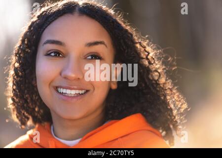 Outdoor-Porträt von schönen glücklich gemischt Rasse biracial afroamerikanischen Mädchen Teenager weibliche junge Frau lächeln mit perfekten Zähnen trägt eine Orange Stockfoto